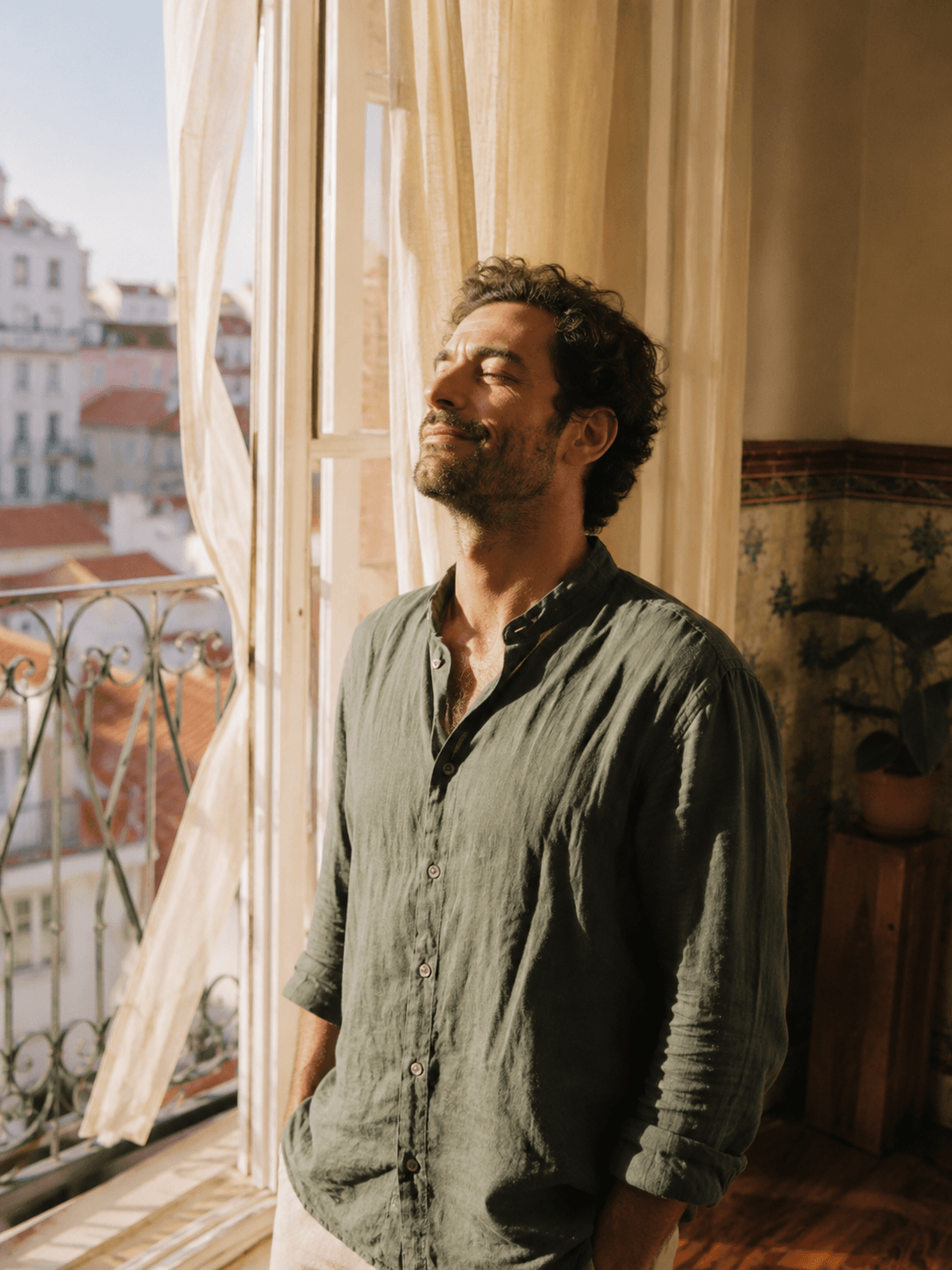 Um homem à janela, sol da manhã na cara, em casa, sem contas na cabeça
